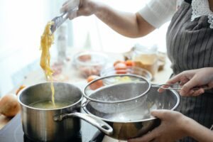 Someone removing cooked pasta after cooking