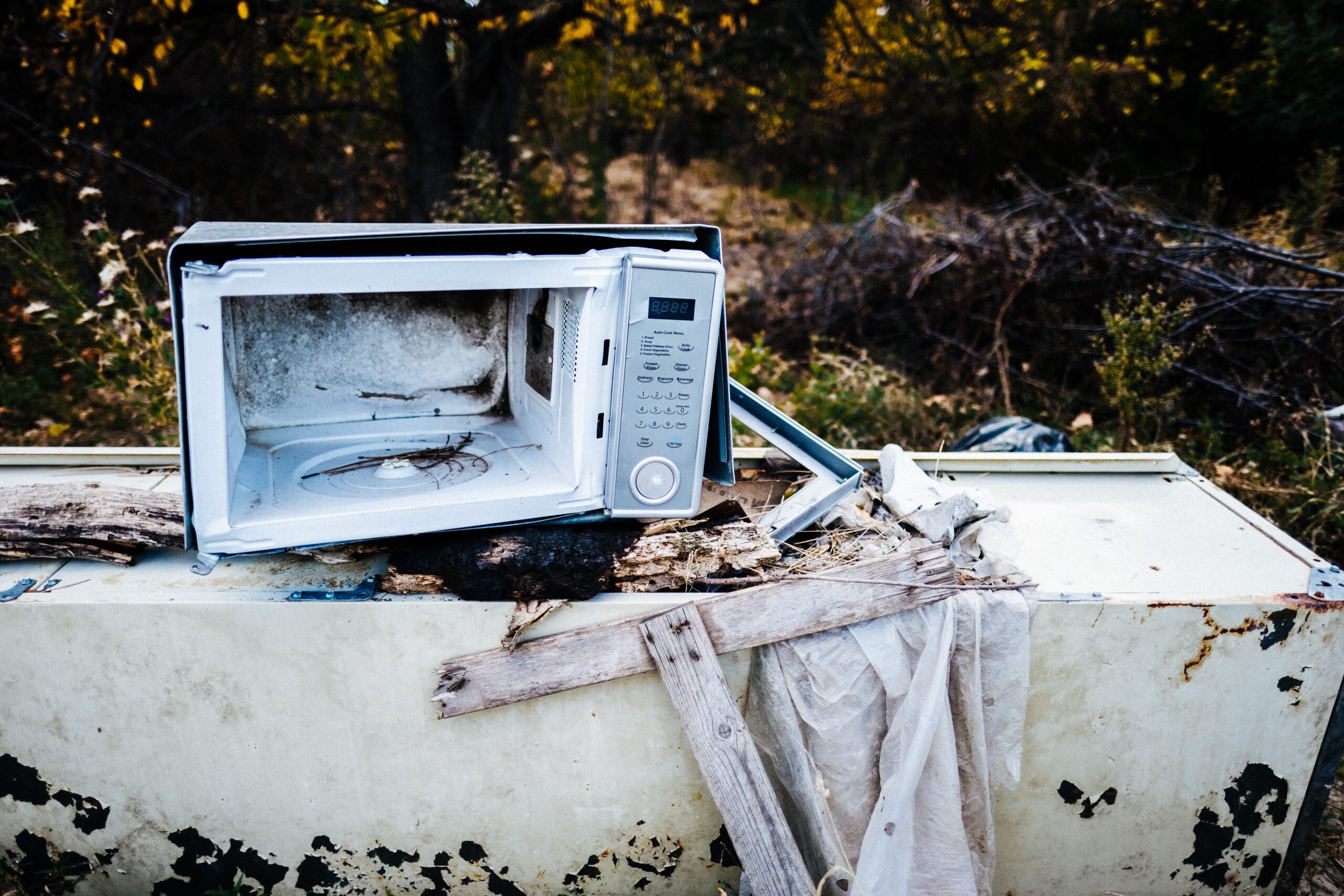Old microwave that is broken, with the door removed.