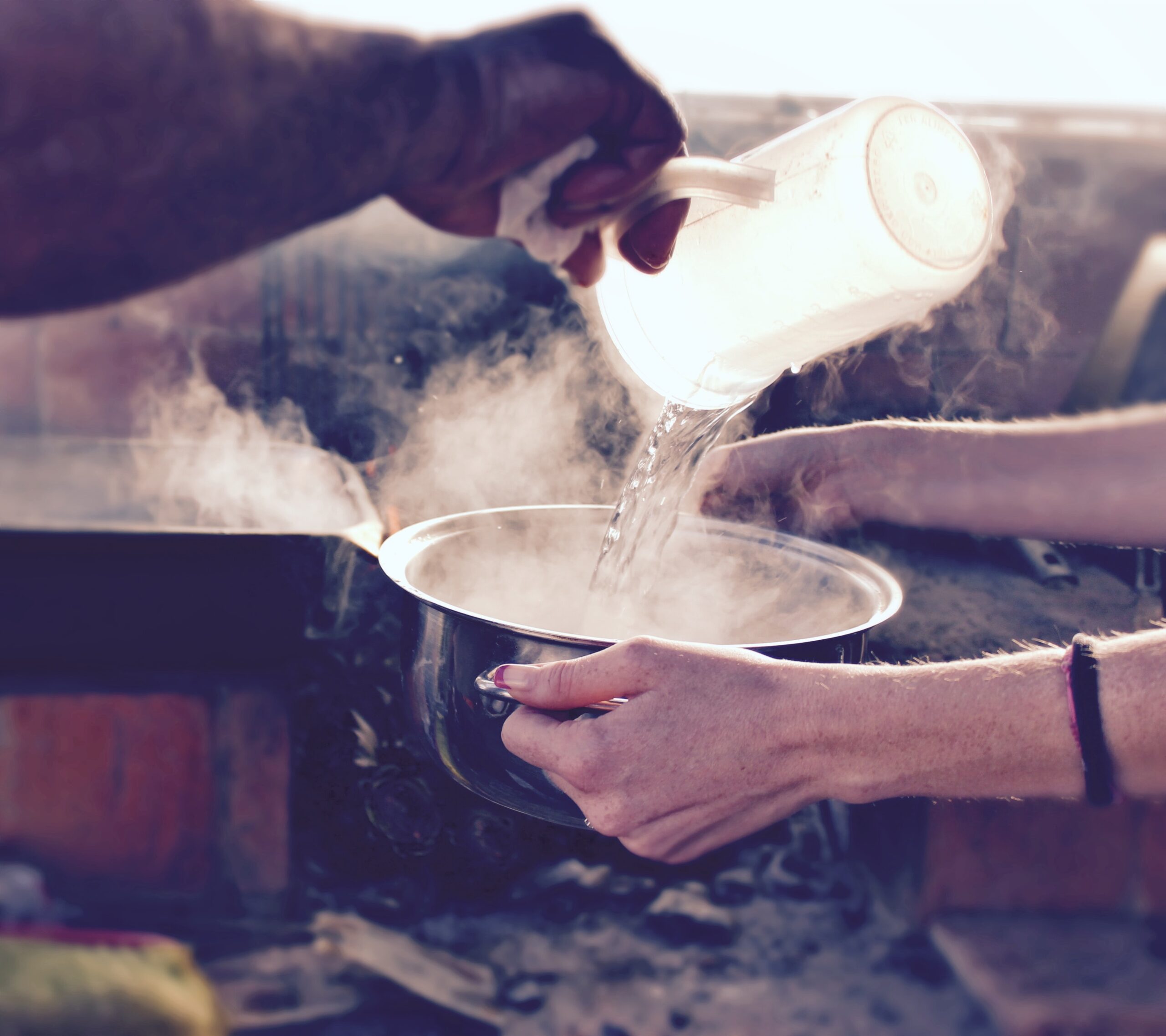 Pouring hot water into a pot to remove burnt on grease